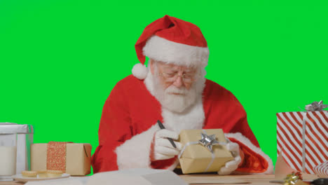 Porträtaufnahme-Des-Weihnachtsmanns,-Der-Ein-Geschenk-Hält-Und-Auf-Eine-Papierrolle-Schreibt