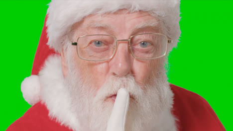 Close-Up-Shot-of-Santa-Shushing-Into-Camera-In-Front-of-Green-Screen