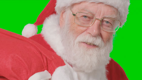 Close-Up-Shot-of-Santa-Walking-Into-and-Out-of-Frame-Holding-a-Sack-with-Green-Screen