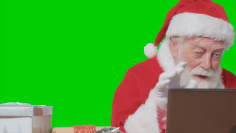 Portrait-Shot-of-Santa-Talking-On-Laptop-Video-Call-In-Front-of-a-Green-Screen