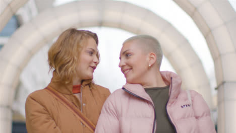 Tracking-Shot-of-Two-Female-Friends-Walking-Through-Arch-Way-Lighting