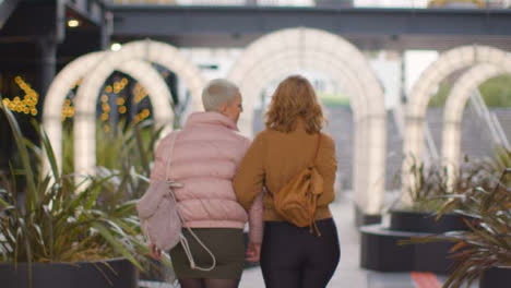Tracking-Shot-Pulling-Away-from-Two-Young-Women-Walking-Through-Archway-Lighting
