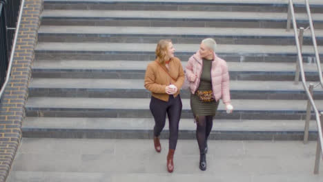 High-Angle-Shot-of-Two-Young-Women-Walking-Down-Steps