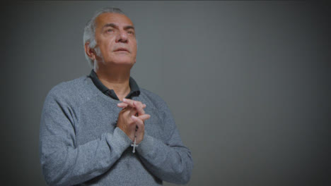 Portrait-Shot-of-Senior-Man-Praying-with-Rosary-Beads-with-Copy-Space