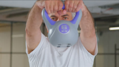 Close-Up-Shot-of-Senior-Man-Using-Kettle-Weight-in-Gym