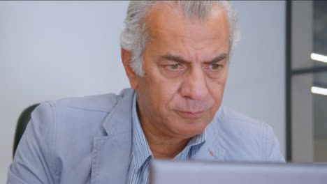 Close-Up-Shot-of-Senior-Man-at-Desk-On-His-Laptop