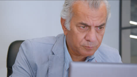 Close-Up-Shot-of-a-Senior-Man-at-Desk-On-His-Laptop