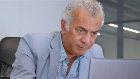 Close-Up-Shot-of-a-Senior-Man-at-a-Desk-On-His-Laptop