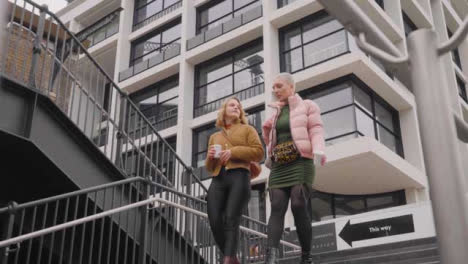 Low-Angle-Shot-of-Two-Young-Women-Walking-Down-Steps