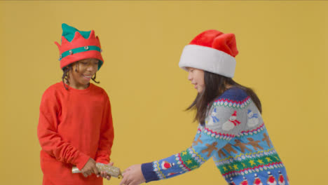 Zwei-Jungs-In-Festlichen-Outfits-Ziehen-Einen-Weihnachtskracher