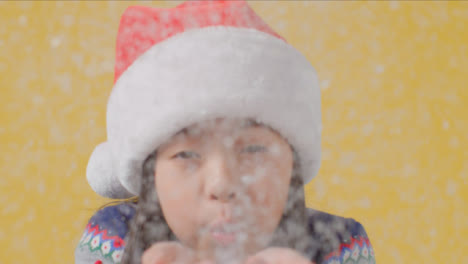 Kind-In-Weihnachtsmütze-Bläst-Schnee-In-Die-Kamera