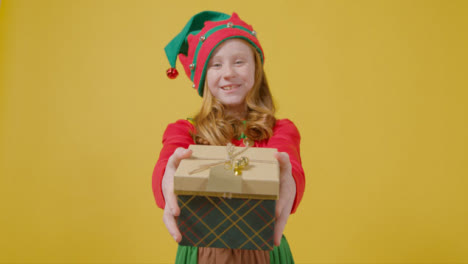 Mädchen-In-Festlichem-Outfit,-Das-Der-Kamera-Ein-Weihnachtsgeschenk-überreicht