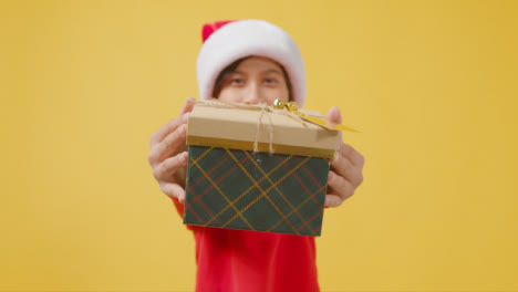Boy-in-Festive-Outfit-Handing-Christmas-Present-to-Camera