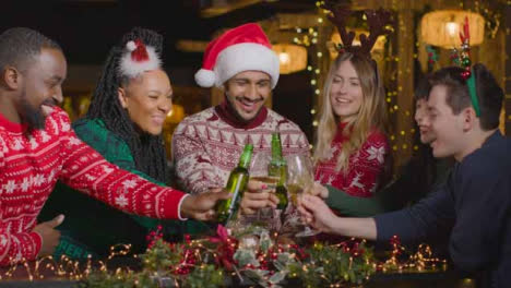 Sliding-Shot-of-Group-of-Friends-Toasting-Drinks-In-Bar-During-Christmas-Celebrations
