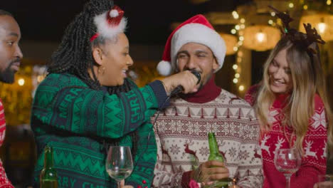Plano-Deslizante-De-Un-Grupo-De-Amigos-Cantando-Karaoke-Durante-Las-Celebraciones-Navideñas