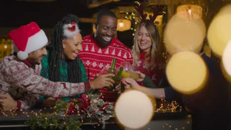 Sliding-Shot-of-Group-of-Friends-Toasting-Their-Drinks-In-Bar-During-Christmas-Celebrations