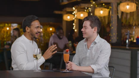 Sliding-Shot-of-Two-Men-Talking-In-a-Bar-Over-Drinks