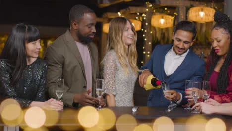 Gleitende-Aufnahme-Von-Freunden,-Die-Während-Der-Neujahrsfeiern-In-Einer-Bar-Champagner-Einschenken?