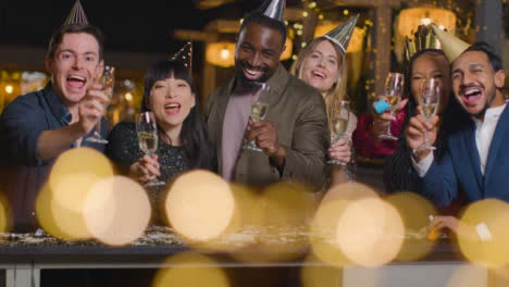 Sliding-Shot-of-Friends-Raising-Glasses-During-New-Year's-Eve-Celebrations-to-Camera