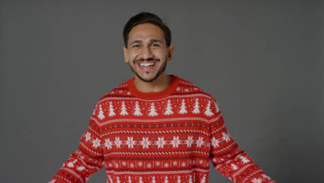 Portrait-Shot-of-Young-Man-In-Christmas-Sweater-Saying-Happy-Christmas