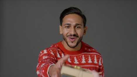 Portrait-Shot-of-Young-Man-In-Christmas-Sweater-Being-Handed-a-Gift