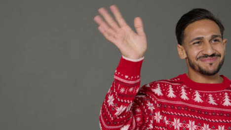 Portrait-Shot-of-Young-Man-In-Christmas-Sweater-Saying-Happy-Christmas-with-Copy-Space