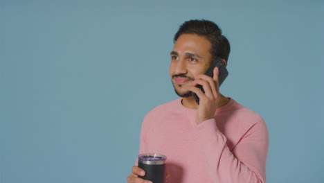 Portrait-Shot-of-Young-Man-Talking-On-Phone-Whilst-Drinking