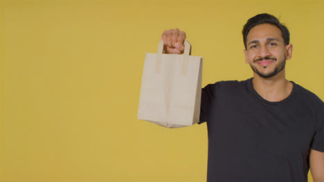 Portrait-Shot-of-Young-Man-Holding-Up-Paper-Bag
