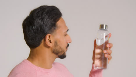 Close-Up-Shot-of-Man-Looking-at-Bottle-and-Then-Smiling