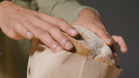 Tracking-Shot-of-a-Young-Man-Unpacking-Bread-and-Smiling