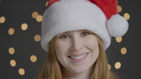 Close-Up-Shot-of-Young-Woman-Smiling-to-Camera-Wearing-a-Christmas-Hat