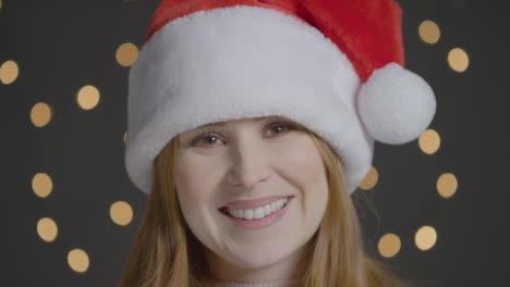 Close-up-Shot-of-a-Young-Woman-Smiling-at-Camera-Wearing-a-Christmas-Hat