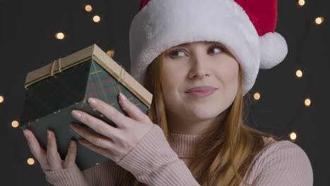 Close-Up-Shot-of-Young-Woman-Shaking-Christmas-Gift
