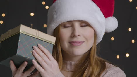 Close-Up-Shot-of-Young-Woman-Smiling-and-Shaking-Christmas-Gift