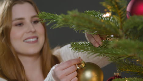 Close-Up-Shot-of-Young-Woman-Smiling-and-Decorating-Christmas-Tree