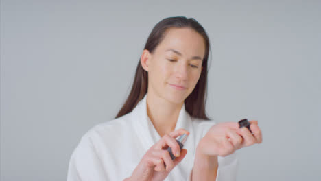 Tiro-Medio-De-Mujer-Sonriendo-Y-Rociando-Perfume