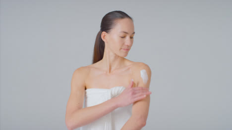 Wide-Shot-of-Young-Woman-Applying-Cream-to-Arms