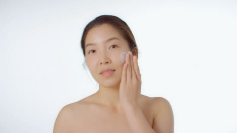 Mid-Shot-of-Young-Woman-Applying-Cream-to-Face
