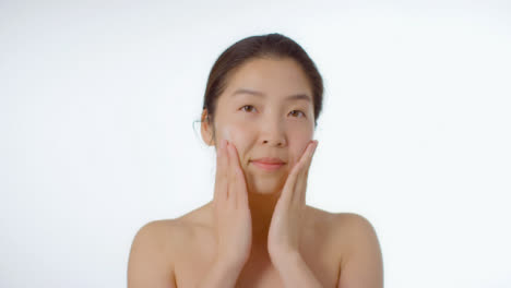 Mid-Shot-of-Young-Woman-Rubbing-Cream-into-Face