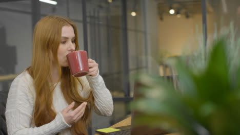 Mid-Shot-of-Woman-Drinking-Hot-Drink-at-Work
