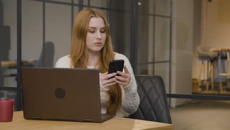 Long-Shot-of-Young-Woman-Texting-on-Phone-at-Work