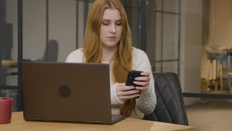 Long-Shot-of-a-Young-Woman-Texting-on-Phone-at-Work