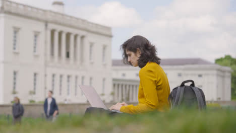 Low-Angle-Wide-Shot-of-Female-Student-Using-Laptop-in-Campus-Park