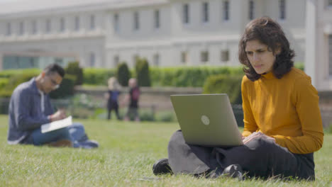 Plano-Medio-De-Una-Estudiante-Mirando-Una-Laptop-En-El-Parque-Universitario