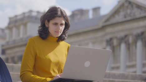 Mid-Shot-of-Female-Student-Using-Laptop-in-College-Steps