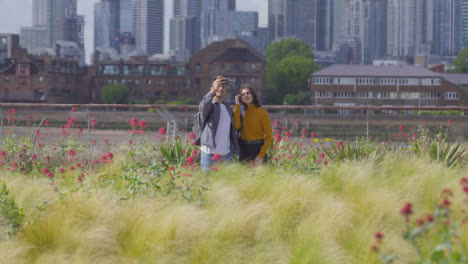 Wide-Shot-of-Two-Friends-Walking-and-Taking-Selfie-Agaisnt-London-Skyline