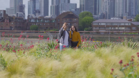 Plano-General-De-Dos-Amigos-Caminando-Y-Tomando-Selfie-Contra-El-Horizonte-De-Londres