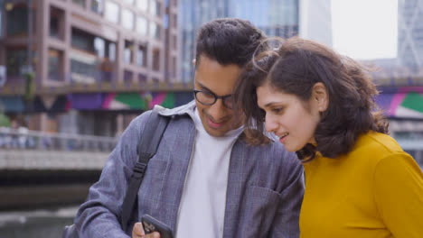 Low-Angle-Shot-Von-Freunden,-Die-Auf-Das-Smartphone-Schauen