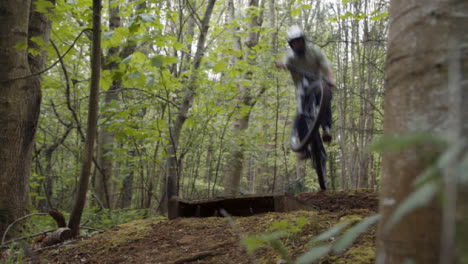 Hombre-En-Bicicleta-De-Montaña-Haciendo-Salto-En-El-Aire-En-Un-Sendero-De-Tierra-A-Través-Del-Bosque