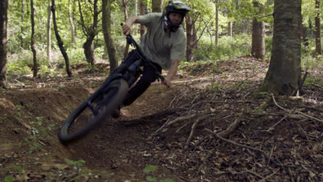 Slow-Motion-Shot-Of-Man-On-Mountain-Bike-Cycling-Along-Dirt-Trail-Through-Woodland-